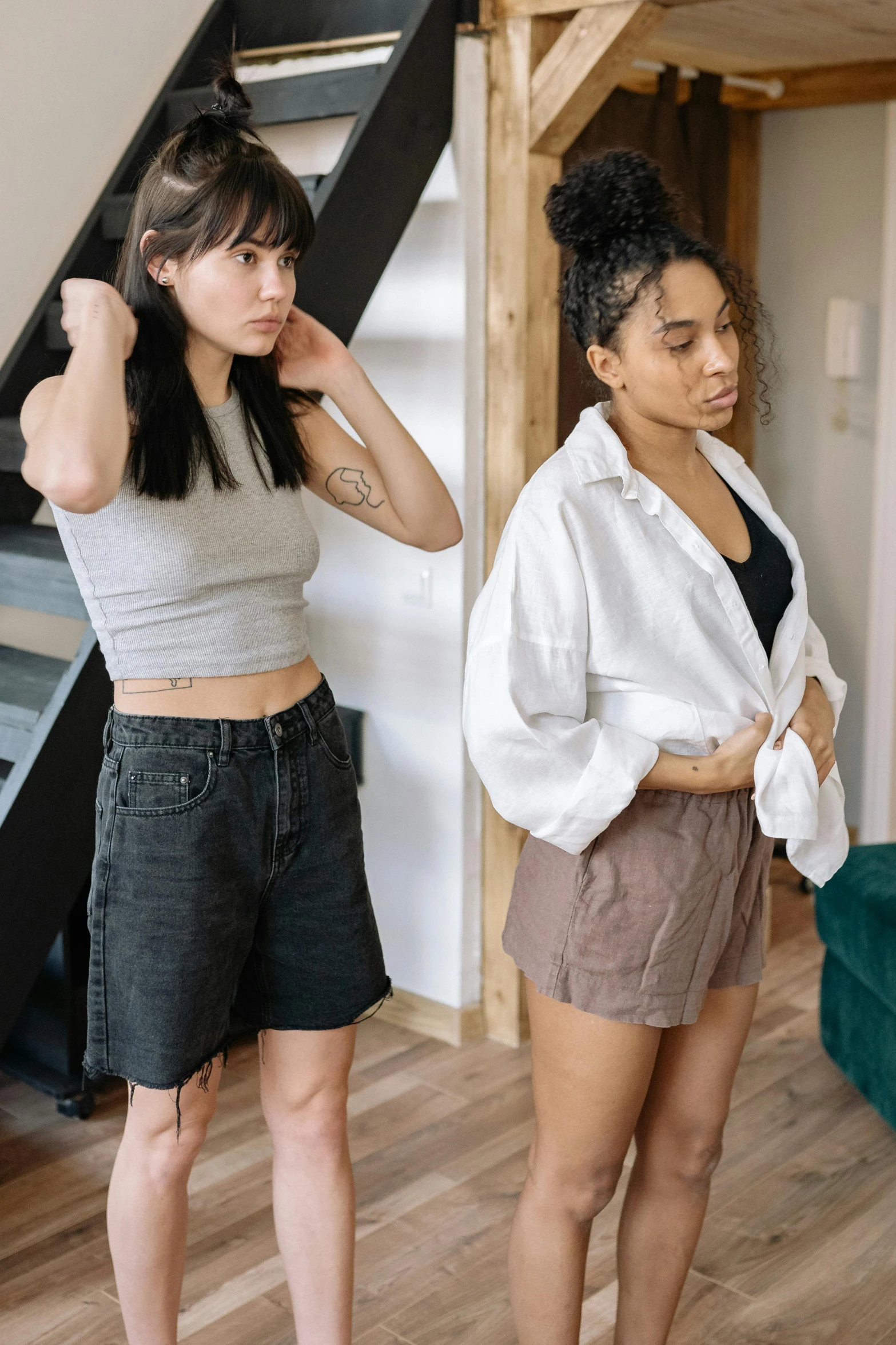 two women standing next to each other in a living room, trending on pexels, bra and shorts streetwear, worried, multiple poses, wearing ragged clothing