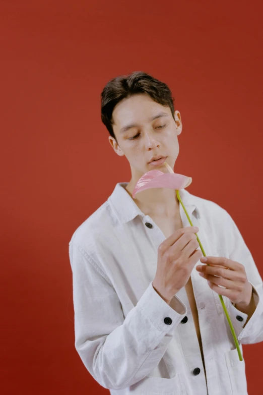 a man in a white shirt holding a pink flower, an album cover, inspired by Russell Dongjun Lu, nonbinary model, lollipop, pale red, looking off to the side