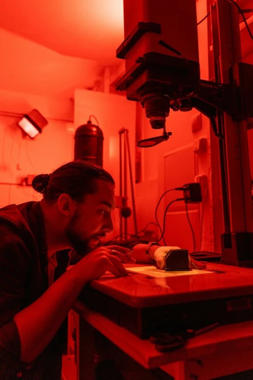 a man sitting in front of a laptop computer, unsplash, holography, red laser scanner, underwater ink env, in a darkly lit laboratory room, orange and red lighting