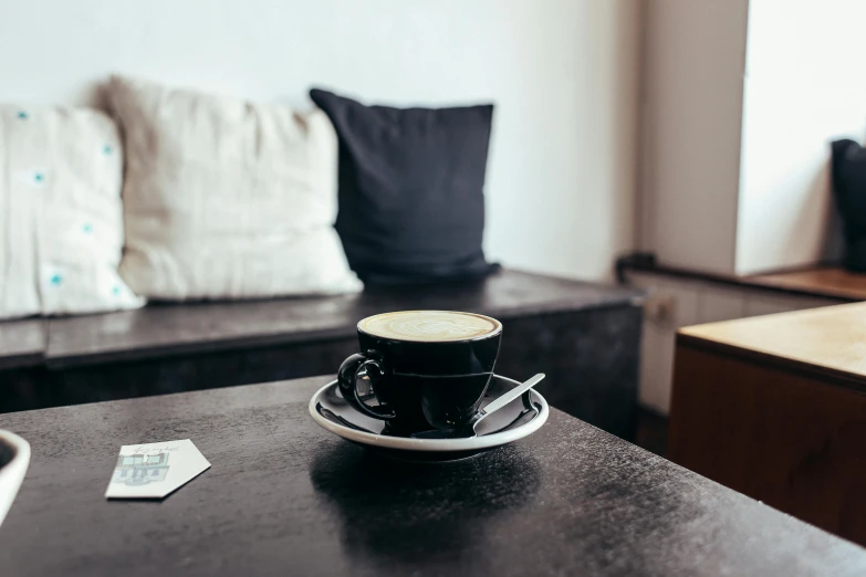 a cup of coffee sitting on top of a table, by Niko Henrichon, lounge, mostly black, scandinavian, kreuzberg