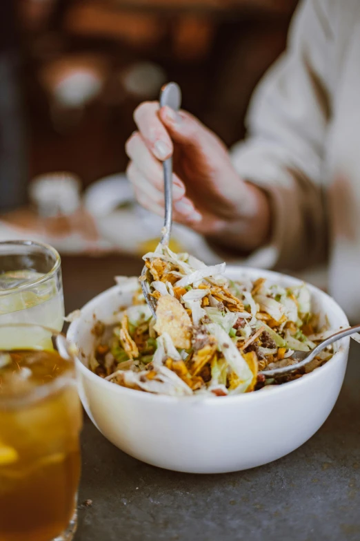 a person sitting at a table with a bowl of food, by Carey Morris, unsplash, with a straw, crispy, white, salad