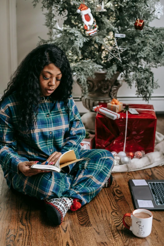 a woman sitting on the floor reading a book, pexels contest winner, happening, wearing festive clothing, in front of a computer, flannel, riyahd cassiem