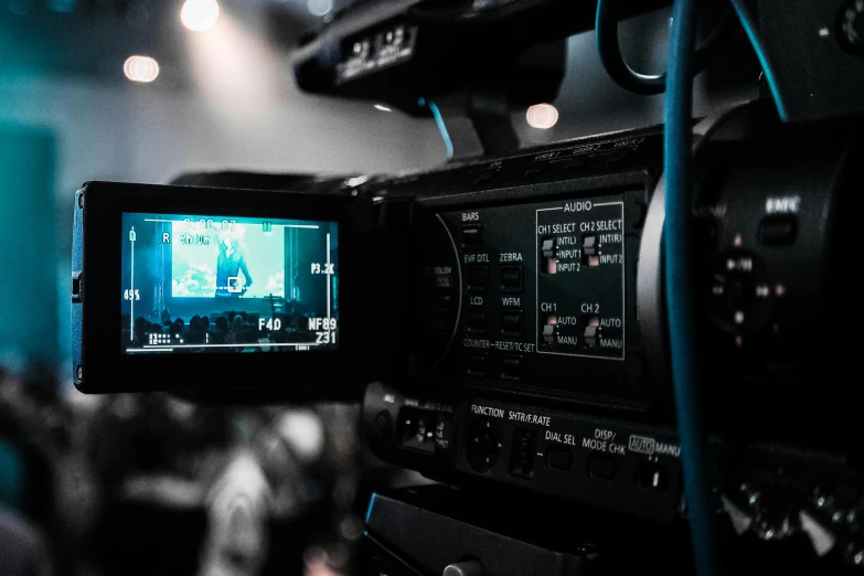 a close up of a video camera on a tripod, trending on pexels, video art, tv screens in background, with subtitles, flash on camera, theatre equipment