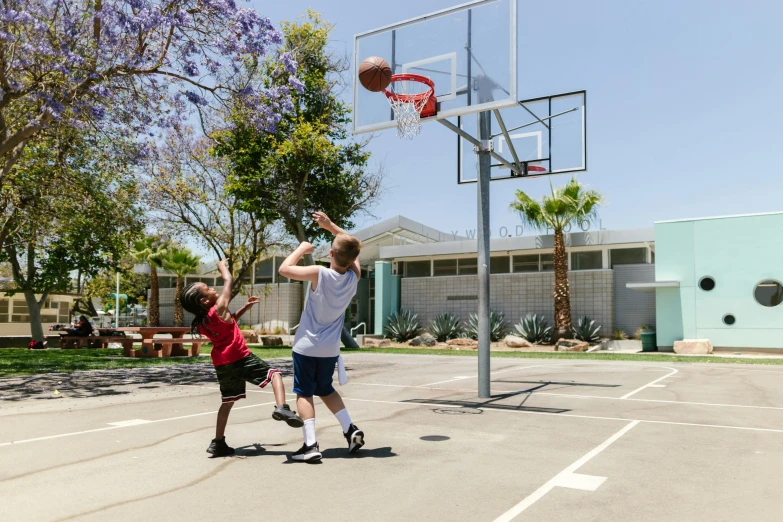 a couple of young men playing a game of basketball, by Gavin Hamilton, pexels contest winner, school courtyard, los angelos, andnorman rockwell, 3 / 4 wide shot