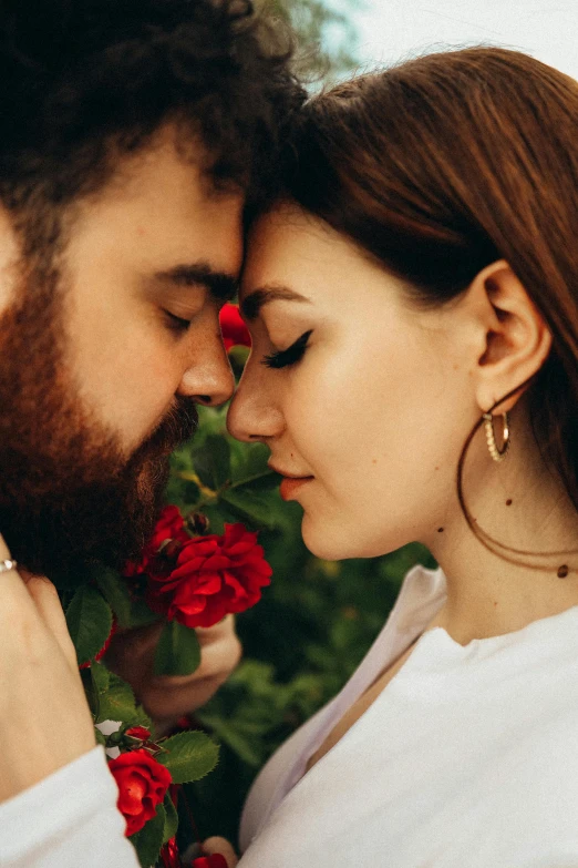 a man and a woman standing next to each other, trending on pexels, romanticism, laying on roses, bushy beard, profile image, intertwined