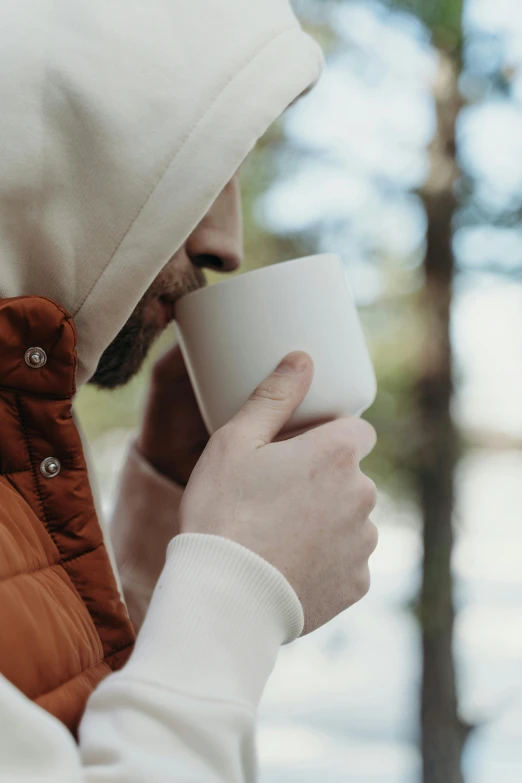 a man in a hooded jacket holding a cup of coffee, enjoying a stroll in the forest, is ((drinking a cup of tea)), multiple stories, guide