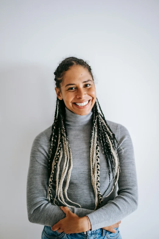 a woman standing in front of a white wall, black hair in braids, darren bartley, teacher, on a black background