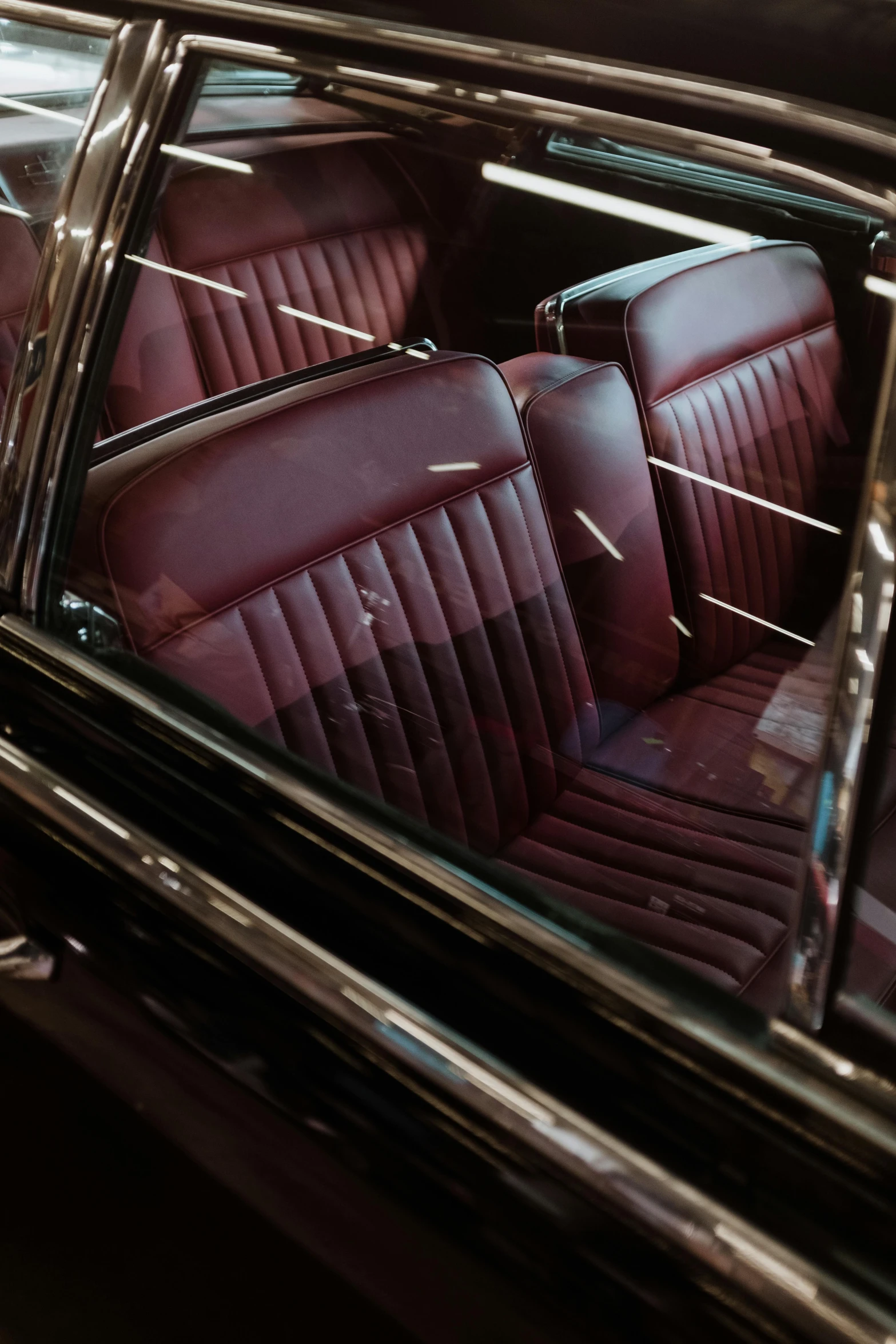 a close up of a car inside of a building, wine red trim, 5 0 s aesthetic, leather couches, shot with sony alpha 1 camera