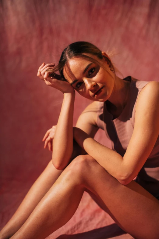 a woman sitting on the ground with her legs crossed, pink volumetric studio lighting, sydney sweeney, in the sun, slide show