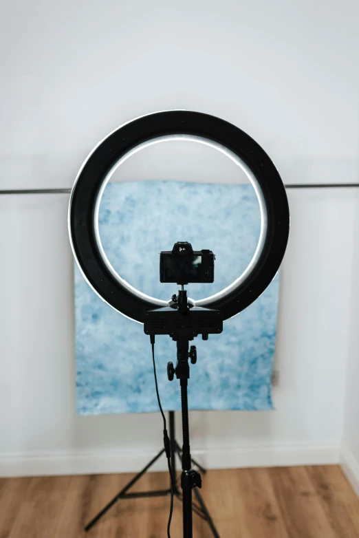 a camera sitting on top of a tripod next to a mirror, ring light, cyan photographic backdrop, on display, loop lighting