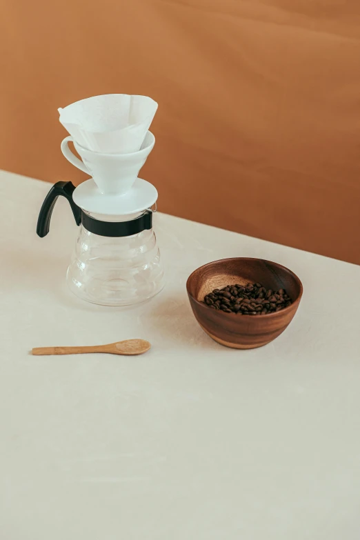 a coffee maker sitting on top of a table next to a bowl, a still life, inspired by Kinichiro Ishikawa, unsplash, sustainable materials, set against a white background, cone, wooden bowl