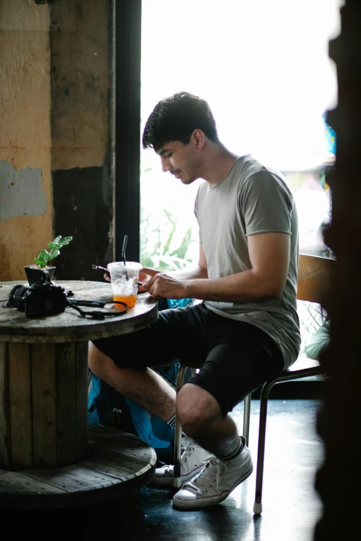 a man sitting at a table writing on a piece of paper, pexels contest winner, wearing black shorts, aussie baristas, sam leach, adventure