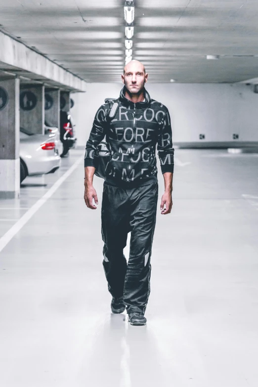 a man is walking in a parking garage, inspired by Nicolas Carone, baroque, wearing a tracksuit, strong presense, worksafe. instagram photo, full body x-force outfit