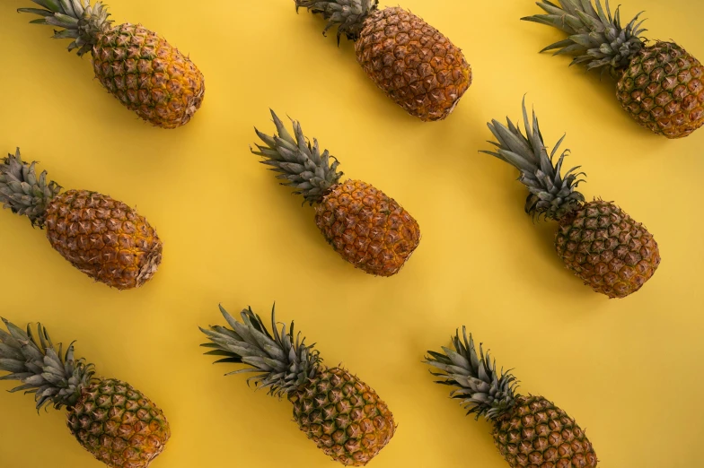 a group of pineapples sitting on top of a yellow surface