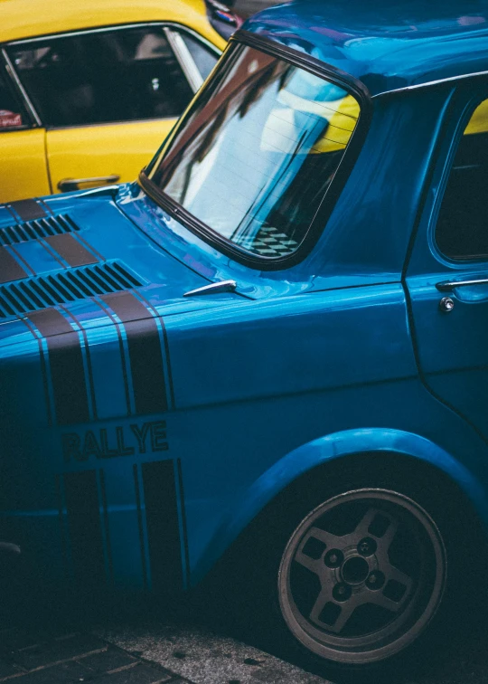 a couple of cars parked next to each other on a street, by Adam Marczyński, unsplash, auto-destructive art, yellow and blue color scheme, close - up profile, square, rally car