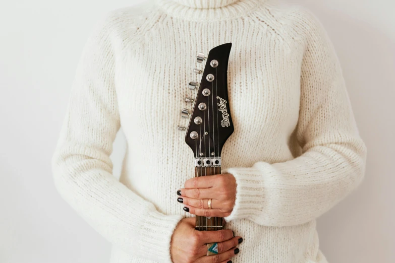 a close up of a person holding a guitar, white sweater, background image, wearing turtleneck, older sister vibes