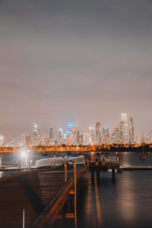 a large body of water with a city in the background, by Liza Donnelly, unsplash contest winner, happening, caulfield, nightlife, background image, near a jetty