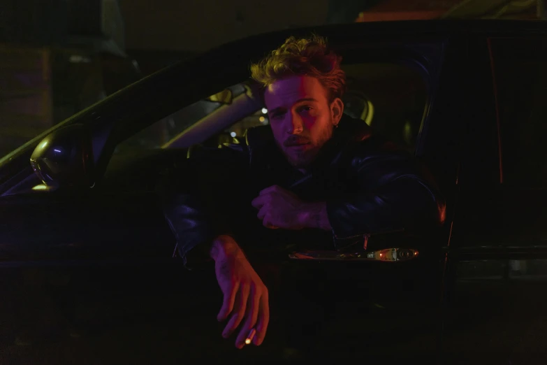 a man sitting in the driver's seat of a car, an album cover, by Elsa Bleda, photorealism, ryan gosling, night time low light, official music video, charlie cox
