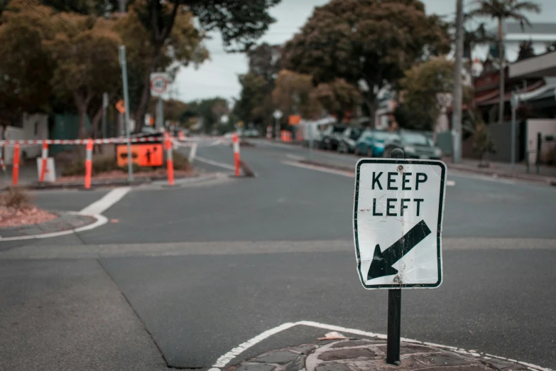 a keep left sign sitting on the side of a road, unsplash, north melbourne street, neighborhood themed, worksafe. instagram photo, thumbnail