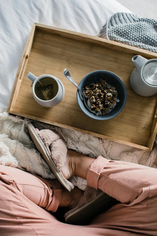 a person laying on a bed with a tray of food, tea, manuka, subtle textures, botanicals