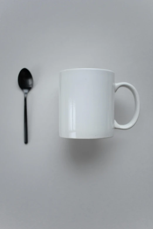 a white cup sitting on top of a table next to a spoon, pexels contest winner, minimalism, mugshots, square, gif, black