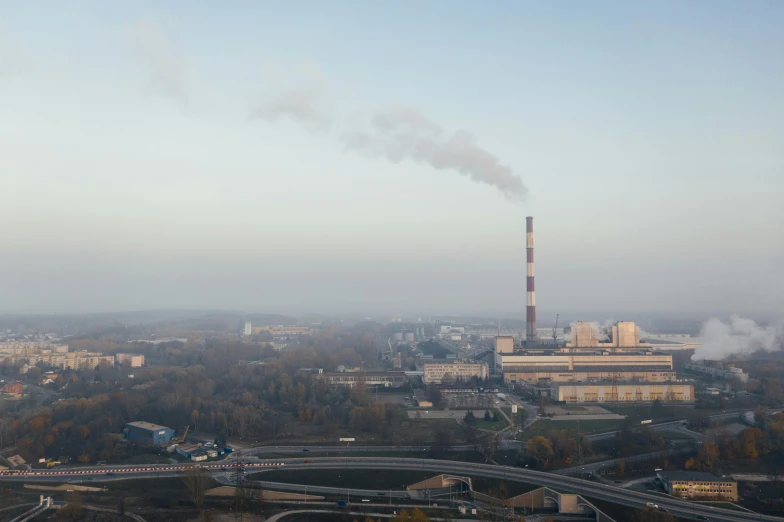 a large factory with a lot of smoke coming out of it, by Adam Marczyński, pexels contest winner, bauhaus, high view, panorama view, a tall, slight haze