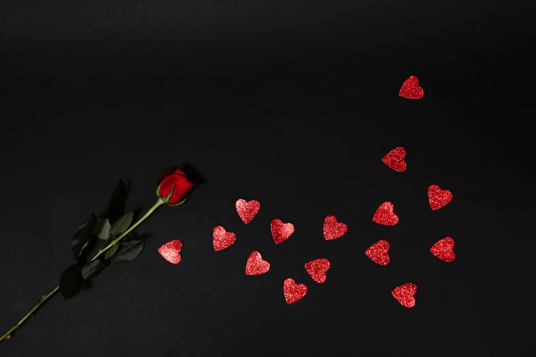 a red rose surrounded by hearts on a black background, by Julia Pishtar, pexels contest winner, background image, minimalist wallpaper, sequins, long shot view
