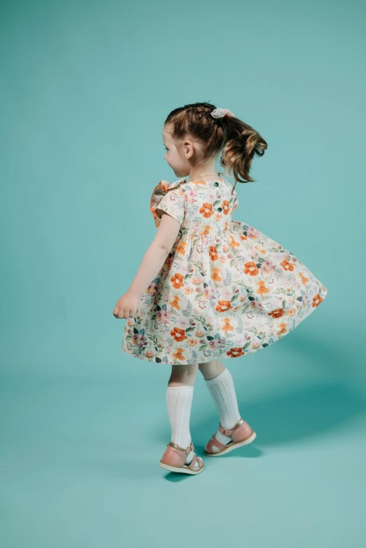 a little girl in a dress on a blue background, inspired by Kate Greenaway, shutterstock contest winner, about to step on you, floral pattern, on grey background, orange and teal