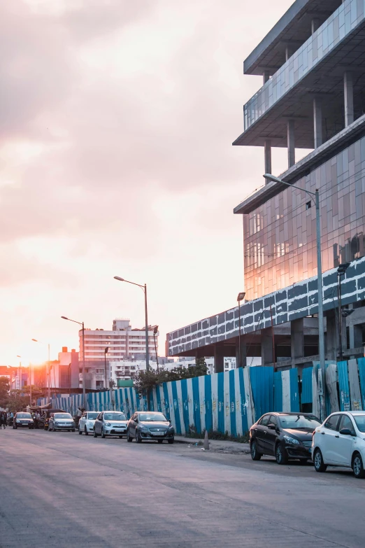 a street filled with lots of traffic next to tall buildings, by Afewerk Tekle, unsplash, bright construction materials, during sunrise, somalia, cuba