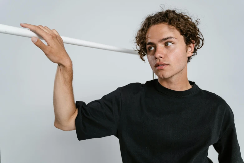 a man holding a baseball bat over his head, an album cover, by Jacob Toorenvliet, pexels contest winner, wearing a black shirt, curly haired, dressed in a white t shirt, default pose neutral expression