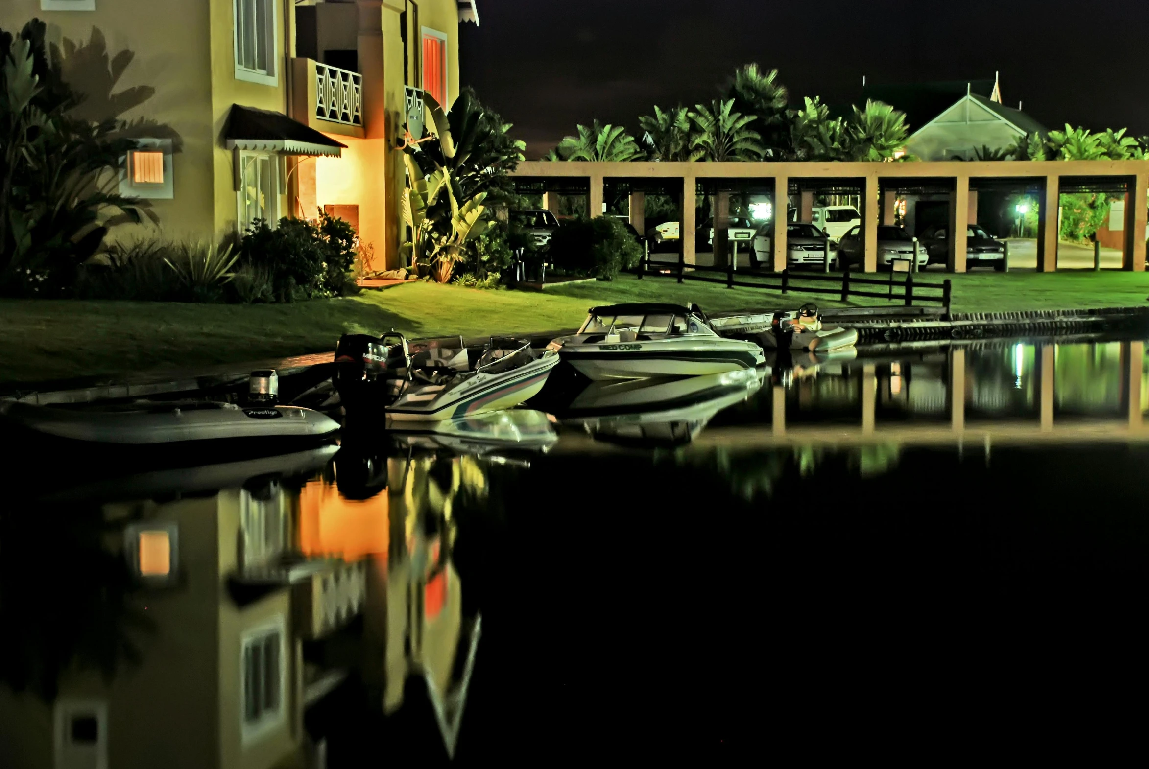 a group of boats sitting on top of a body of water, by Felipe Seade, pexels contest winner, photorealism, night outside, reflective pool, backyard, water reflection!!!!!