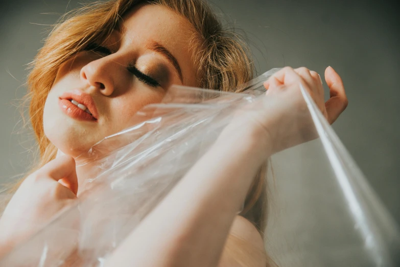 a woman holding a plastic bag over her head, inspired by Elsa Bleda, trending on pexels, hyperrealism, covered breasts, redhead woman, soft vinyl, with professional makeup