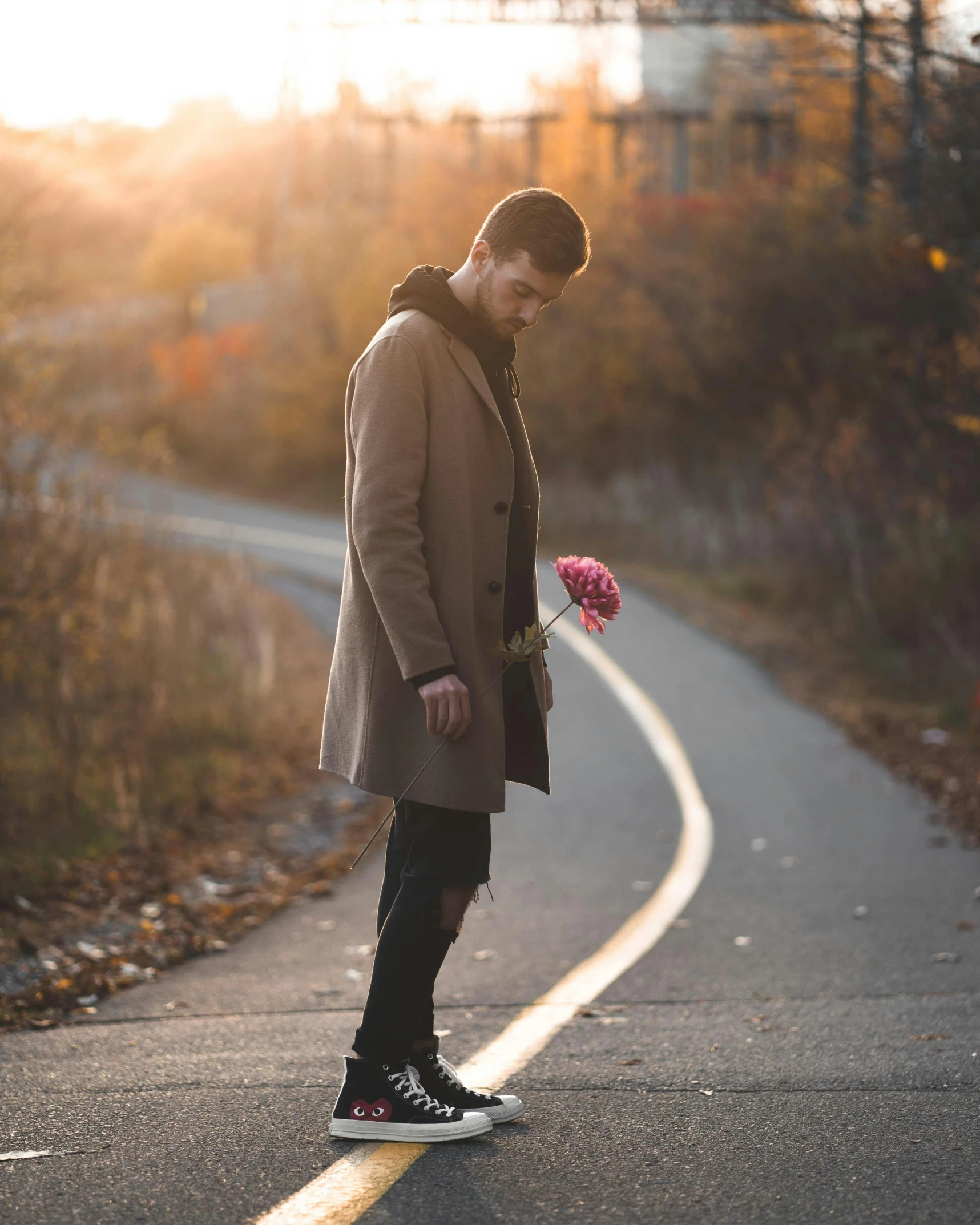 a man standing on the side of a road holding a bunch of flowers, pexels contest winner, romanticism, loveable guy, non-binary, wearing a long coat, broken heart