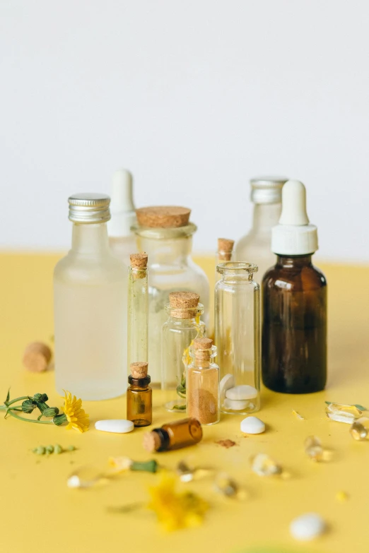 a group of bottles sitting on top of a yellow table, trending on pexels, botanicals, vials, white, seeds