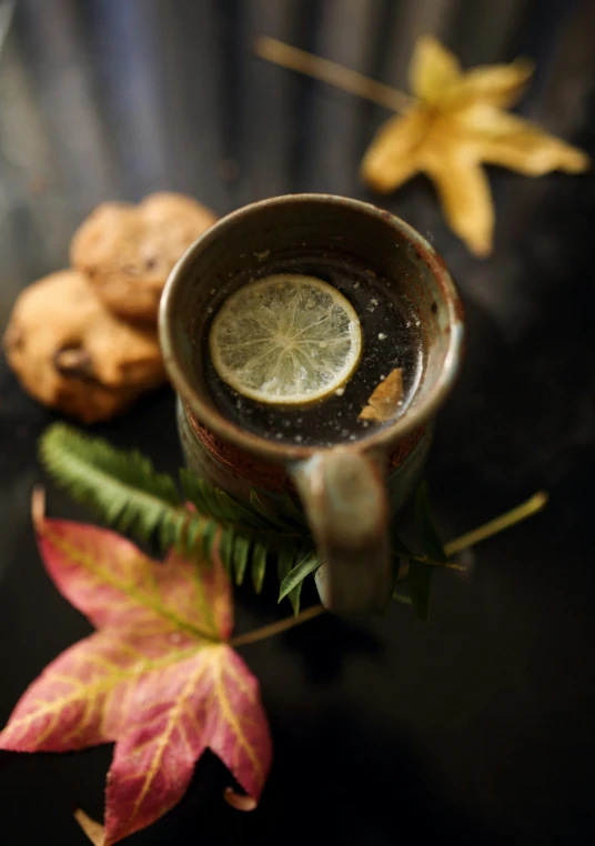 a cup of coffee sitting on top of a table, leaf, ginger, lemon, thumbnail