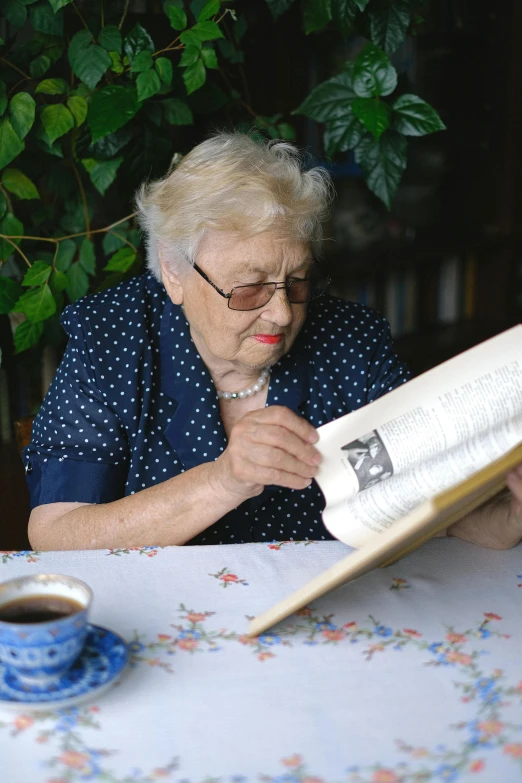 a woman sitting at a table reading a book, a very macular woman in white, very old, trending photo, taken in the late 2010s