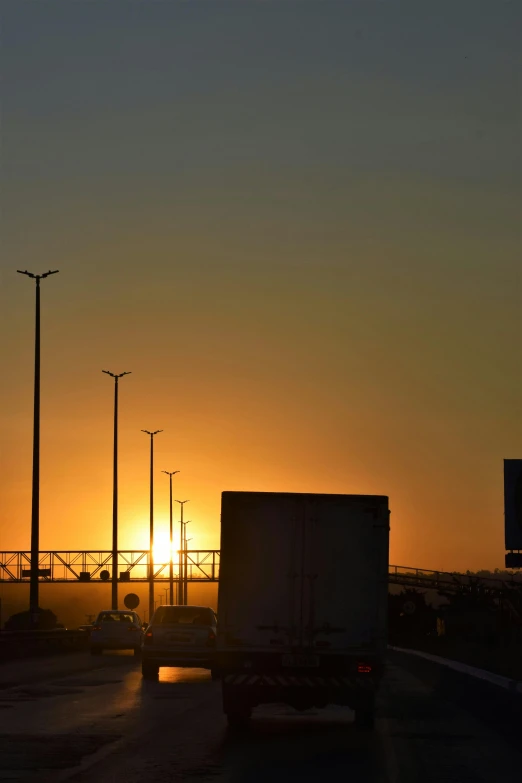 a truck driving down a highway at sunset, by Sven Erixson, square, sunshafts, gateway, nice sunset