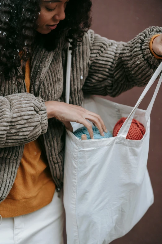 a woman holding a shopping bag in the snow, pexels contest winner, process art, wearing a white sweater, yarn, with two front pockets, fluid bag