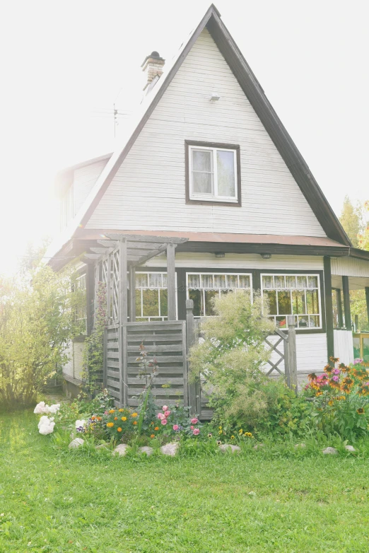 a white house sitting on top of a lush green field, a picture, romanticism, midsommar - t, profile image, cottagecore flower garden, cabin