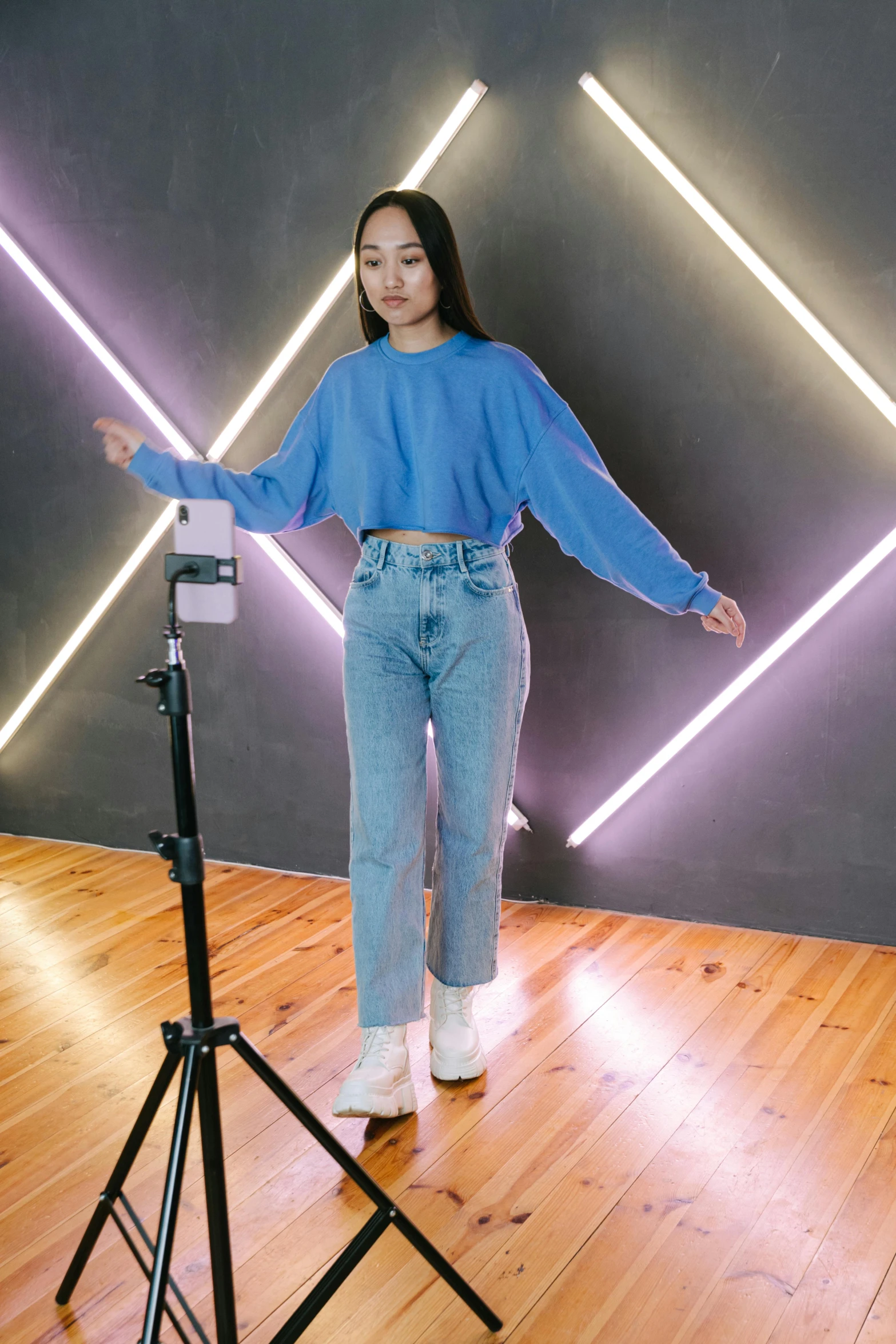 a woman standing in front of a camera on a tripod, a hologram, by Robbie Trevino, featured on instagram, baggy jeans, blue sweater, heonhwa choe, ready to model