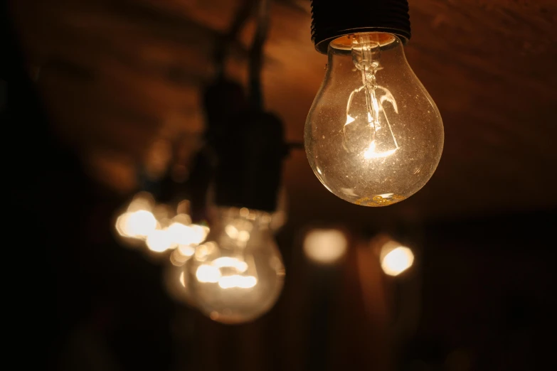 a bunch of light bulbs hanging from a ceiling, by David Donaldson, pexels, warm dim light, a wooden, medium closeup, atmospheric lighting - n 9