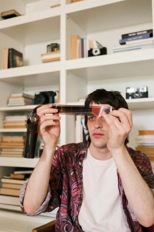 a man holding a camera up to his face, an album cover, by Nina Hamnett, center parted curtain bangs, studying in a brightly lit room, librarian, transparent background