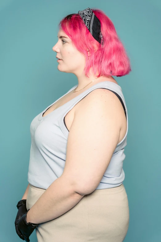 a woman with pink hair standing in front of a blue background, by Rachel Reckitt, wearing a cropped black tank top, morbidly obese, profile image, wearing : tanktop