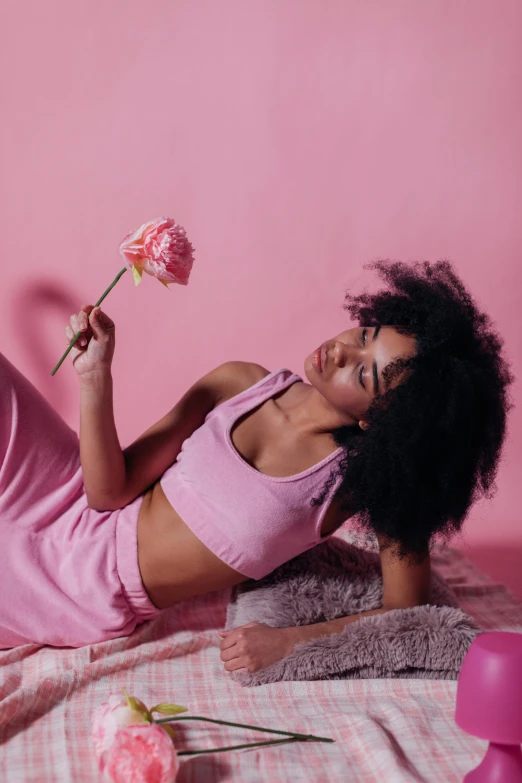 a woman laying on a bed holding a flower, by Dulah Marie Evans, trending on pexels, aestheticism, pink clothes, with afro, cottagecore!! fitness body, concept photoset