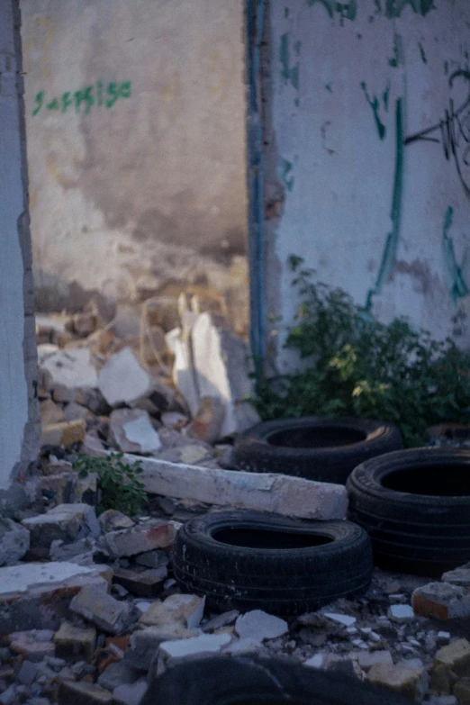 a pile of tires sitting on top of a pile of rubble, an album cover, unsplash, crumbled wall in jerusalem, color footage, alleys, shot from a distance