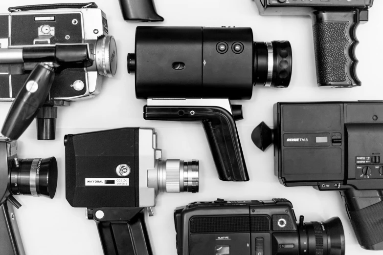 a group of cameras sitting on top of a table, a black and white photo, movie firearms, 2 4 0 p footage, ecommerce photograph, handheld