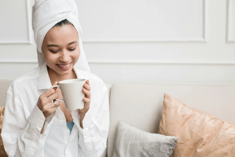 a woman with a towel wrapped around her head holding a cup, pexels contest winner, manuka, with an elegant smile, afternoon hangout, tech robes