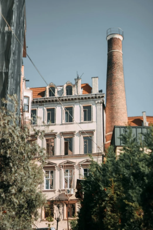 a couple of buildings that are next to each other, by Adam Marczyński, unsplash contest winner, art nouveau, chimney, large tall, low quality photo, slightly sunny weather