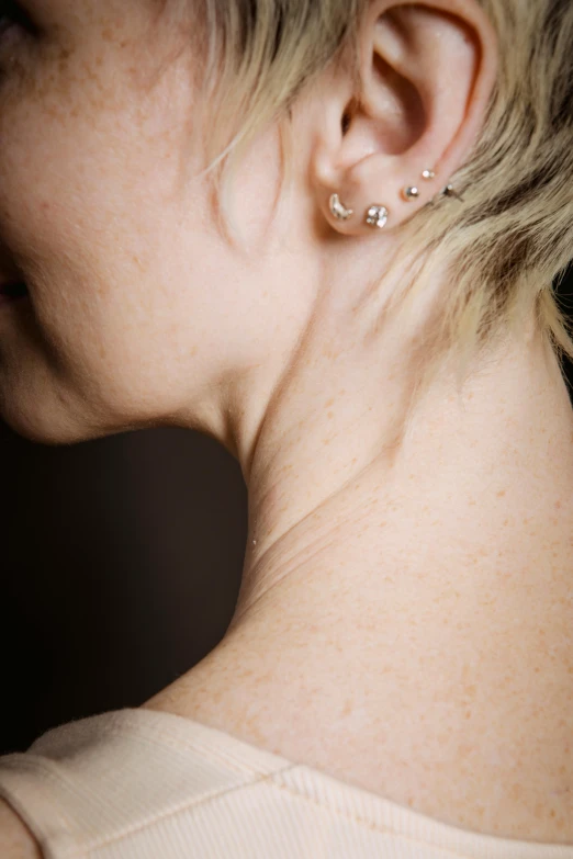 a close up of a person with ear piercings, incoherents, bare chest, side - view, high angle shot, side lights