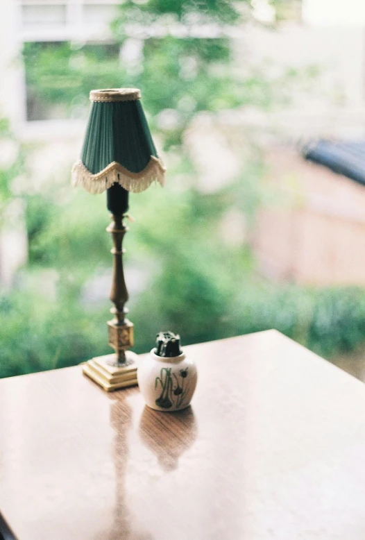 a lamp sitting on top of a wooden table, a tilt shift photo, by Elsa Bleda, unsplash, f 1.4 kodak portra, a green, antiques, miniature porcelain model